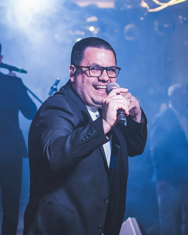 El cantante de Mandu'arã sonriendo con el micrófono en un cumpleaños